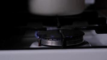 Ignition of the gas burner on the stove in the kitchen. Use of natural resources, economy, cooking on fire. Close-up video