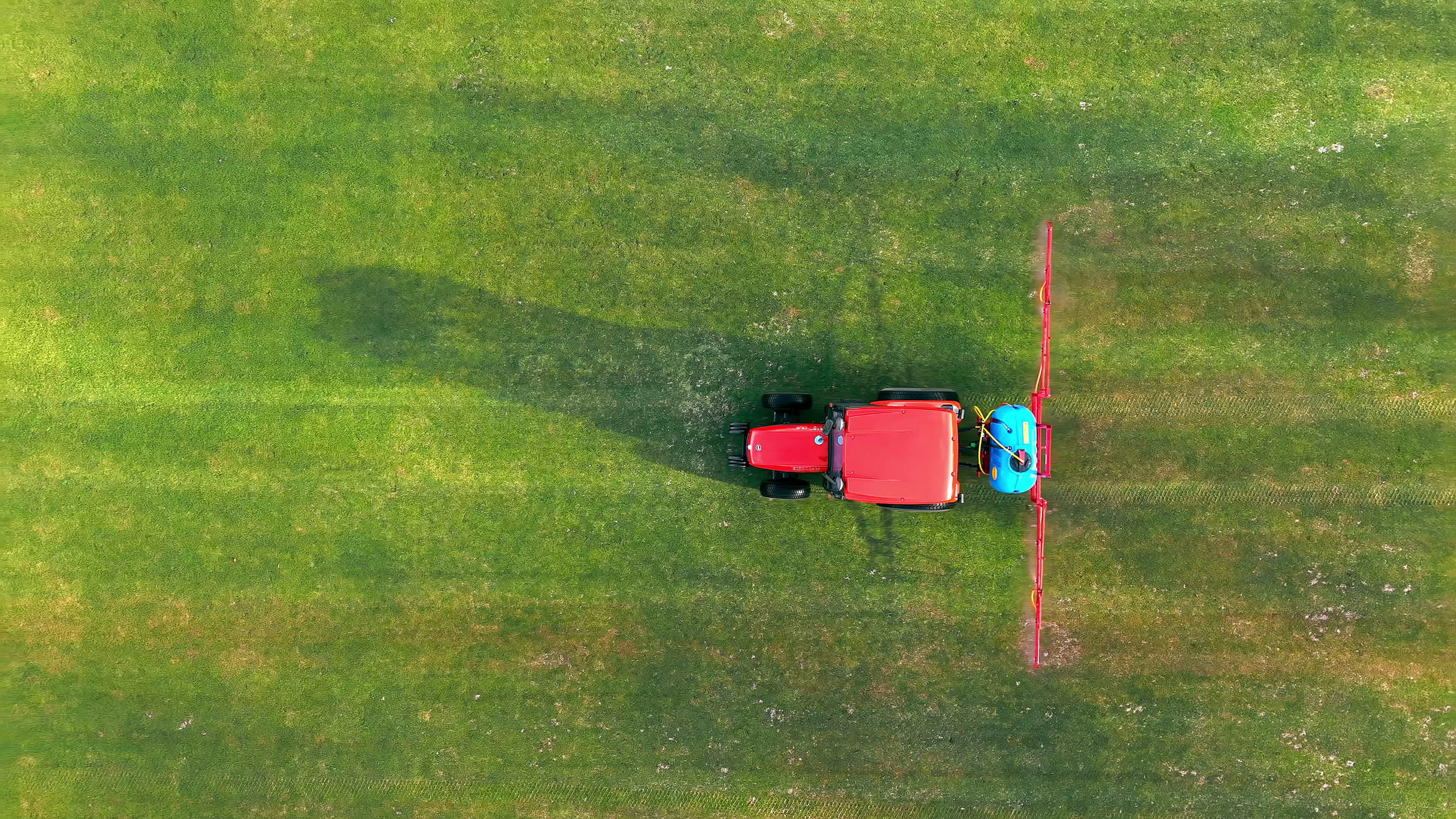 Aerial top view The tractor sprinkles the grass of the football field