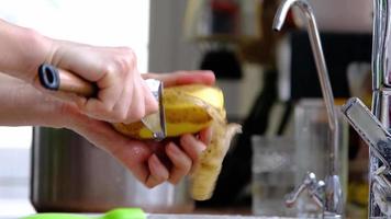 De las mujeres manos pelar crudo patatas con un especial cuchillo con un vegetal policía debajo un corriente de agua en el cocina. cocinando, ahorro agua, Respetuoso del medio ambiente utilizar de recursos video