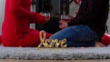 Man and woman in love date at home are sitting near the fireplace stove with a burning fire on a cozy rug. Valentine's Day, happy couple, love story, relationships video