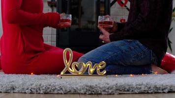 el hombre y la mujer enamorados en casa están sentados cerca de la estufa de la chimenea con un fuego ardiente en una alfombra acogedora. día de san valentín, pareja feliz, historia de amor, relaciones video