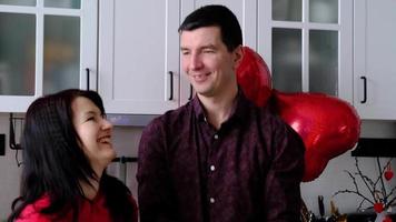 Mann und Frau im Liebe Datum beim Zuhause im Küche werfen Herzen Konfetti und Luftballons. Valentinstag Tag, glücklich Paar, Liebe Geschichte. Liebe Nest, Gehäuse zum jung Familie