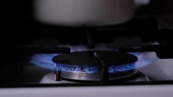 Ignition of the gas burner on the stove in the kitchen. Use of natural resources, economy, cooking on fire. Close-up video