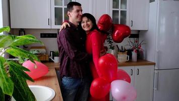 hombre y mujer enamorados citan en casa en la cocina felices abrazos. día de san valentín, pareja feliz, historia de amor. nido de amor, vivienda para familia joven video