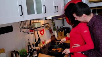 hombre y mujer en amor fecha a hogar en cocina ellos hornear panqueques y contento abrazos. San Valentín día, contento pareja, amor historia. amor nido, alojamiento para joven familia video