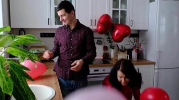 Mann und Frau im Liebe Datum beim Zuhause im Küche werfen Herzen Konfetti und Luftballons. Valentinstag Tag, glücklich Paar, Liebe Geschichte. Liebe Nest, Gehäuse zum jung Familie