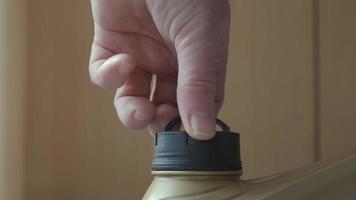 A man's hand unscrews a canister of car oil, close-up. video