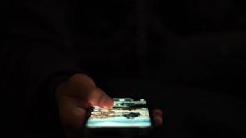 hands scrolling social media video sharing app in the dark