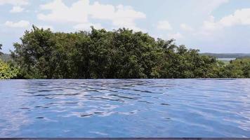 Infinity swimming pool with summer nature tree background bright sky day time. Loop footage video.