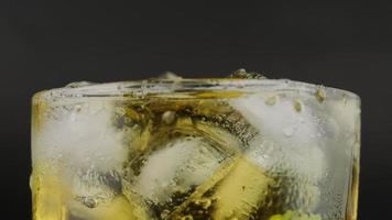 Shot of hand pouring cold tequila from a bottle with lemon and salt on black background. A glass of tequila with lemon slices and splashing. video