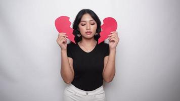Beautiful young Asian woman expressed her sadness while holding broken heart isolated on white background