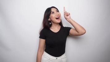 Excited Asian woman dressed in black shirt, pointing at the copy space on top of her, isolated by white background video