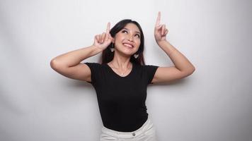 Excited Asian woman dressed in black shirt, pointing at the copy space on top of her, isolated by white background video