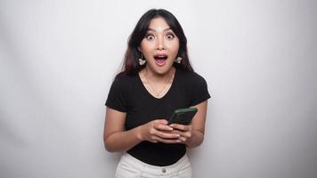 A portrait of a happy Asian woman dressed in black shirt and holding her phone, isolated by white background video