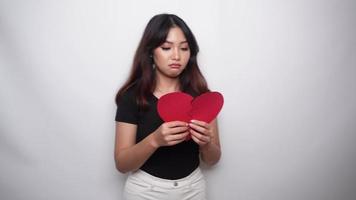 skön ung asiatisk kvinna uttryckt henne sorg medan innehav bruten hjärta isolerat på vit bakgrund video