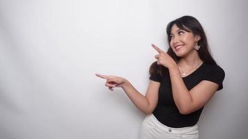 Excited Asian woman dressed in black shirt, pointing at the copy space beside her, isolated by white background video