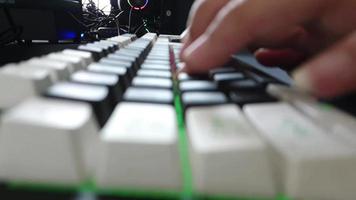 ein Hand ist Tippen auf ein Spieler Klaviatur. diese Tastatur hat Weiß und schwarz Farben mit bunt Beleuchtung. video