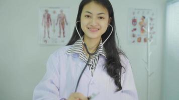 sonriente joven mujer médico cardiólogo vistiendo blanco médico Saco y estetoscopio demostración manos corazón forma mirando a cámara. cardiología cuidado de la salud, amor y medicina caridad concepto, retrato. video