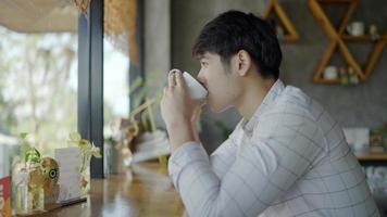 handsome asian man drinking coffee in a cup smile and look forward happily during the morning time video