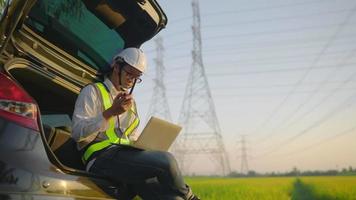 Engineer Man In Helmet Working on laptop.Electricity Towers. Electrical Engineer With High Voltage Electricity Pylon At Sunset. Voltage Tower Support. Electricity Work Concept. video