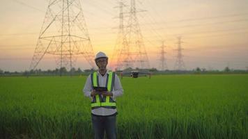 un eléctrico ingeniero forzando un zumbido a inspeccionar alto voltaje polos antes de comenzando un proyecto asignado por el organización durante el puesta de sol hora video