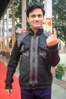 New Delhi, India - December 04 2022 - Unidentified people showing their ink-marked fingers after casting votes in front of polling booth of east Delhi area for MCD local body Elections 2022 photo