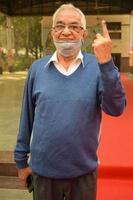 New Delhi, India - December 04 2022 - Unidentified people showing their ink-marked fingers after casting votes in front of polling booth of east Delhi area for MCD local body Elections 2022 photo