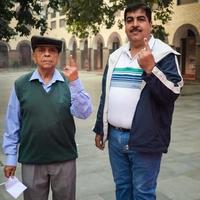 New Delhi, India - December 04 2022 - Unidentified people showing their ink-marked fingers after casting votes in front of polling booth of east Delhi area for MCD local body Elections 2022 photo