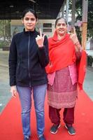 New Delhi, India - December 04 2022 - Unidentified people showing their ink-marked fingers after casting votes in front of polling booth of east Delhi area for MCD local body Elections 2022 photo