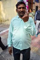 New Delhi, India - December 04 2022 - Unidentified people showing their ink-marked fingers after casting votes in front of polling booth of east Delhi area for MCD local body Elections 2022 photo