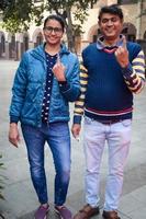 New Delhi, India - December 04 2022 - Unidentified people showing their ink-marked fingers after casting votes in front of polling booth of east Delhi area for MCD local body Elections 2022 photo