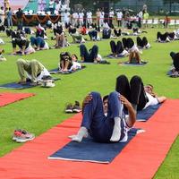 New Delhi, India, June 21 2022 - Group Yoga exercise session for people at Yamuna Sports Complex in Delhi on International Yoga Day, Big group of adults attending yoga class in cricket stadium photo