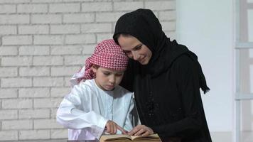 contento Arabo madre e figlio insieme seduta su il divano e lettura un' libro. video