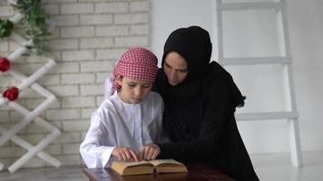 contento Arabo madre e figlio insieme seduta su il divano e lettura un' libro. video