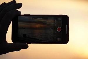 Hands taking selfie with smartphone at sunset in key west photo