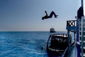 maldivo hombre saltando en agua y buceo desde barco foto