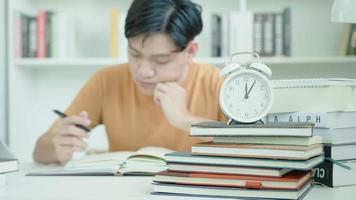 homem estudante asiático tem ansiedade por causa dos exames, o homem se prepara para o teste e aprende lições na biblioteca. estresse, desespero, pressa, leitura mal-entendida, desencorajado, expectativa, conhecimento, cansado video