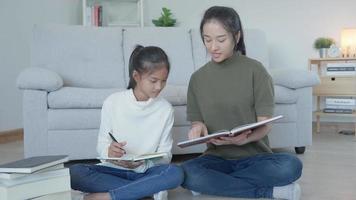 Mother teaching lesson for daughter. Asian young little girl learn at home. Do homework with kind mother help, encourage for exam. Asia girl happy Homeschool. Mom advise education together.