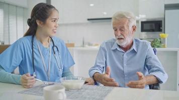 soignant alimentation bouillie à déprimé Masculin patient. dérangé vieux homme se plaindre la vie à sentiment sérieux. femelle infirmière soutien et consolant lui video