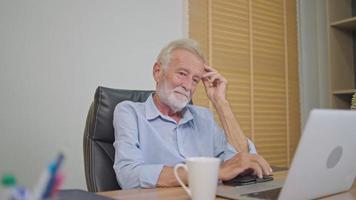 senior gepensioneerd Mens gebruik makend van laptop en echt denken van werk Bij werken bureau. handelaar of investeerder na pensioen. bedrijf analyse video