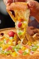 classic pizza with cheese on the table in a cafe on a wooden stand with a cut triangular piece and a pizza knife photo