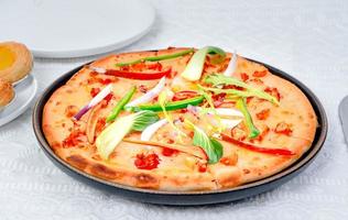 classic pizza with cheese on the table in a cafe on a wooden stand with a cut triangular piece and a pizza knife photo