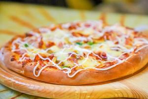 classic pizza with cheese on the table in a cafe on a wooden stand with a cut triangular piece and a pizza knife photo