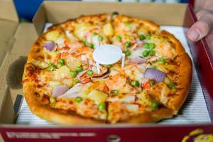 classic pizza with cheese on the table in a cafe on a wooden stand with a cut triangular piece and a pizza knife photo