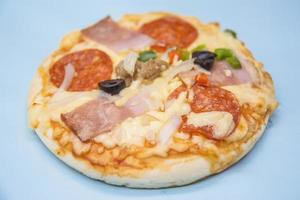 classic pizza with cheese on the table in a cafe on a wooden stand with a cut triangular piece and a pizza knife photo
