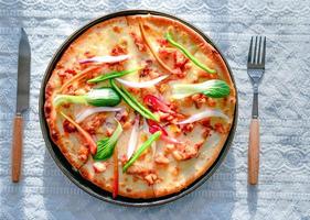 classic pizza with cheese on the table in a cafe on a wooden stand with a cut triangular piece and a pizza knife photo