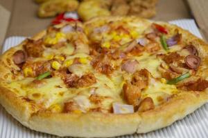 classic pizza with cheese on the table in a cafe on a wooden stand with a cut triangular piece and a pizza knife photo