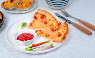 classic pizza with cheese on the table in a cafe on a wooden stand with a cut triangular piece and a pizza knife photo