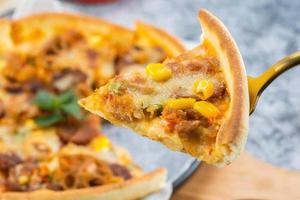 classic pizza with cheese on the table in a cafe on a wooden stand with a cut triangular piece and a pizza knife photo