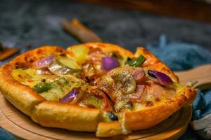 classic pizza with cheese on the table in a cafe on a wooden stand with a cut triangular piece and a pizza knife photo